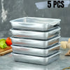 Five stackable stainless steel food storage containers arranged on a gray surface.