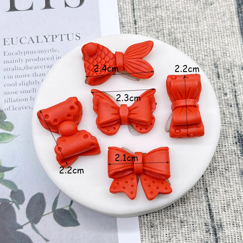 A collection of orange silicone baking molds shaped like bows and other decorative items on a white plate.