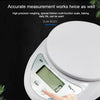 A hand is placing a finger on the display of a white digital kitchen scale with a weighing unit visible.
