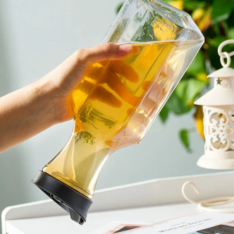 A hand holds a clear plastic water bottle filled with yellow liquid, demonstrating the flip lid feature.