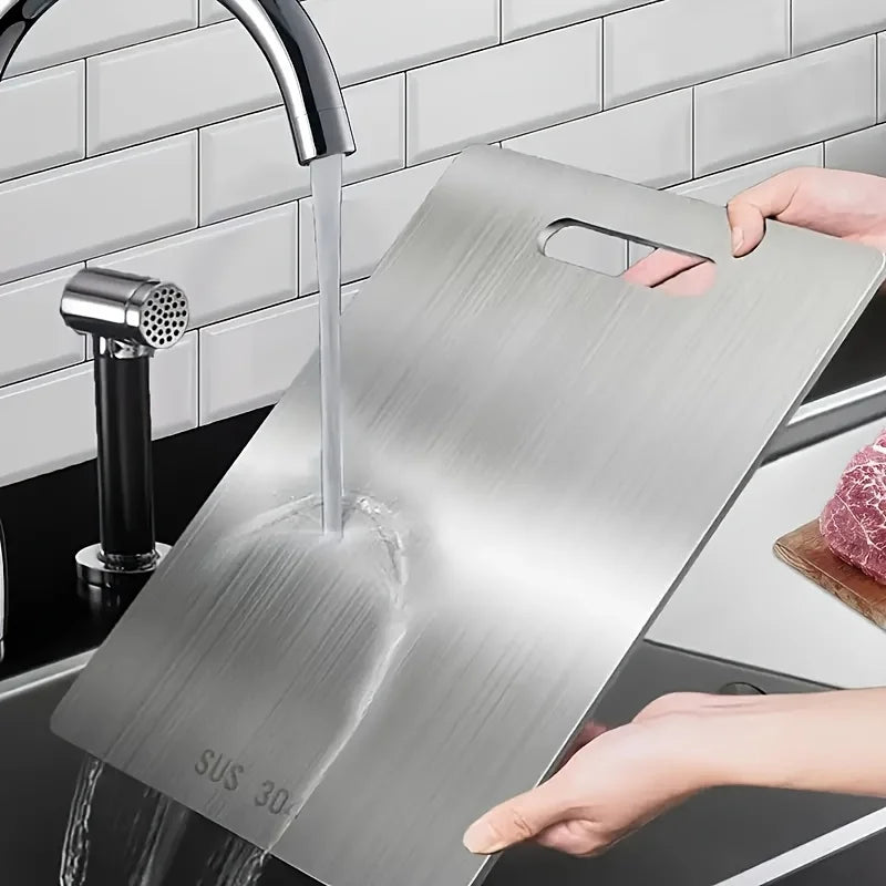 A stainless steel cutting board is being used under a kitchen faucet.
