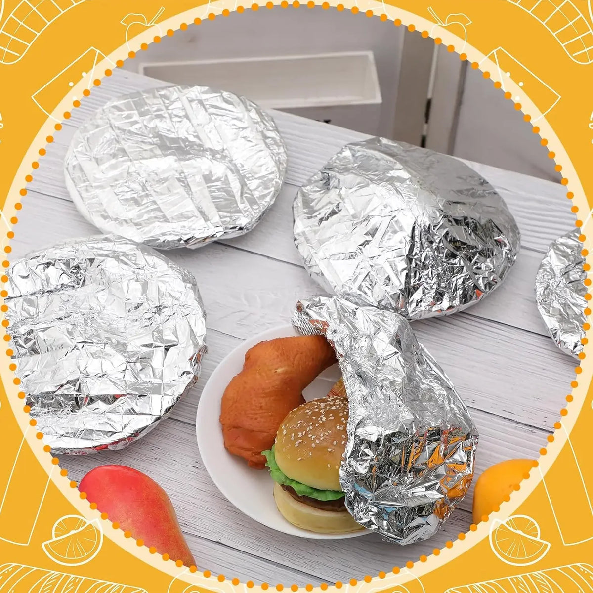 A plate of food items wrapped in aluminum foil, including a burger and a piece of bread.