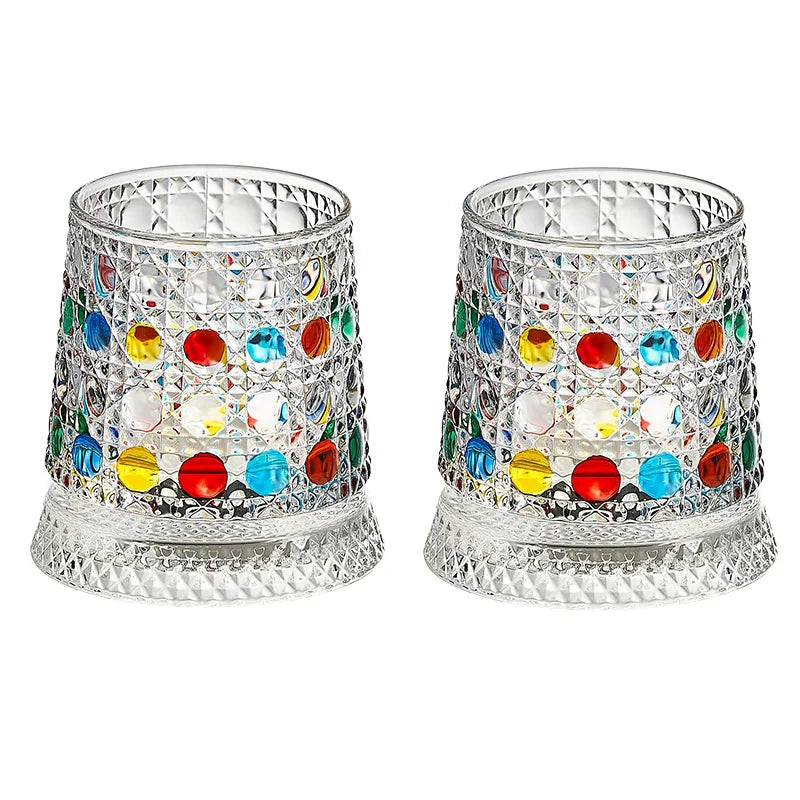 A pair of ornate, cut crystal rotating whiskey glasses with colorful glass inserts.
