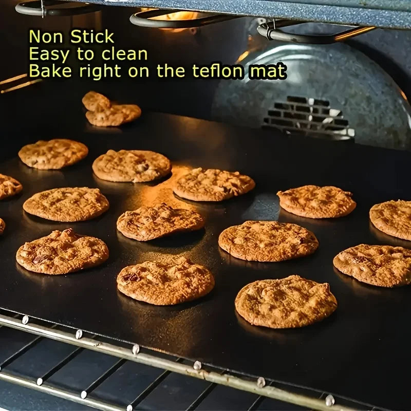 A black baking sheet filled with golden-brown cookies baked on a non stick silicone mat in an oven.