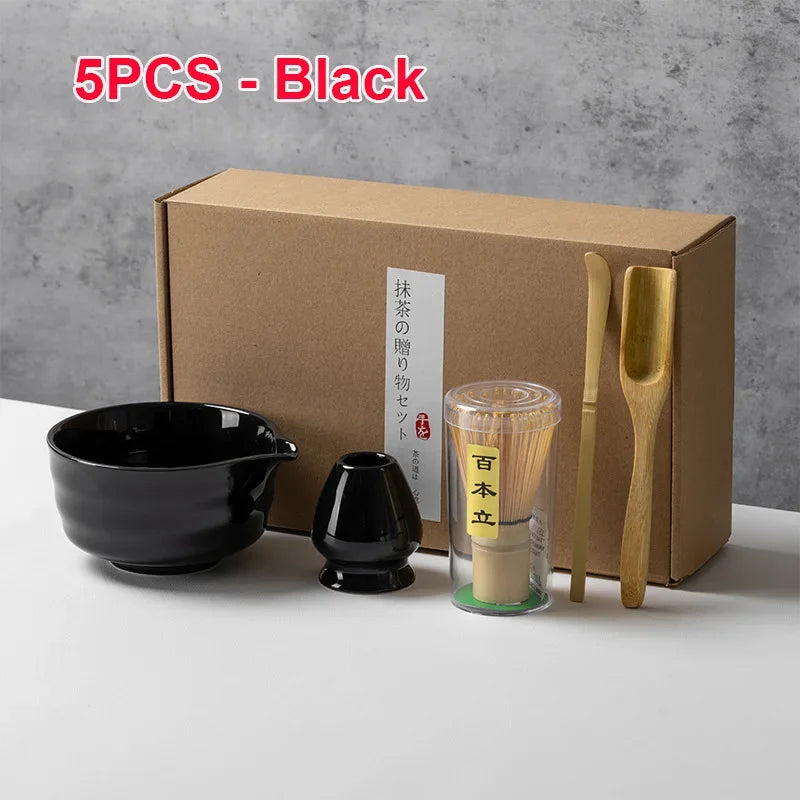 Un juego de cinco utensilios de té matcha negros, incluyendo cuencos y utensilios de bambú, empaquetados en una caja de cartó