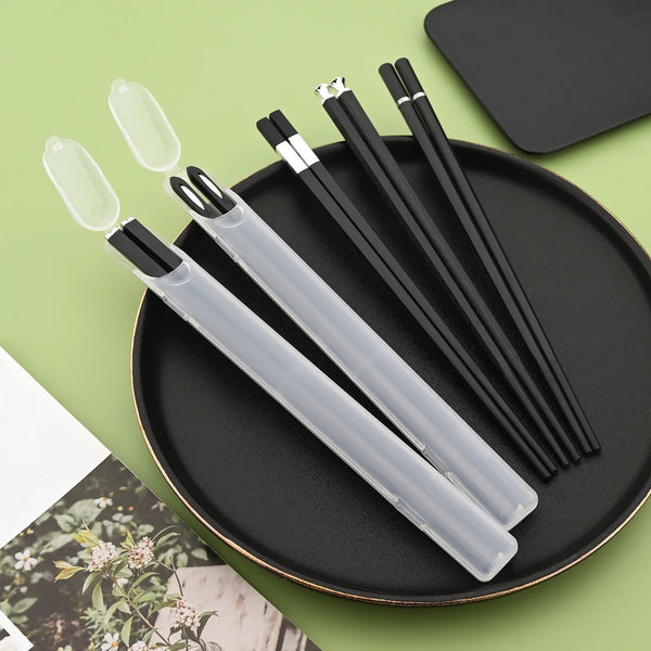 Elegantes schwarz-silbernes Legierung-Stäbchenset auf einer schwarzen Platte.