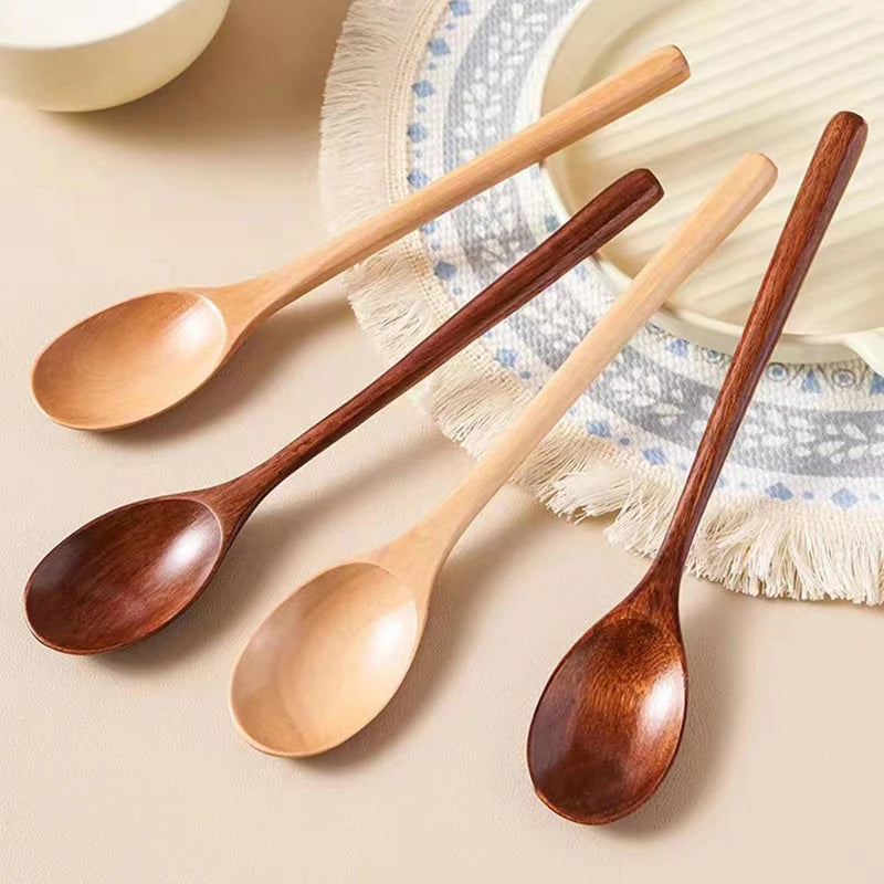 A set of four wooden spoons with varying sizes and finishes arranged on a light background.