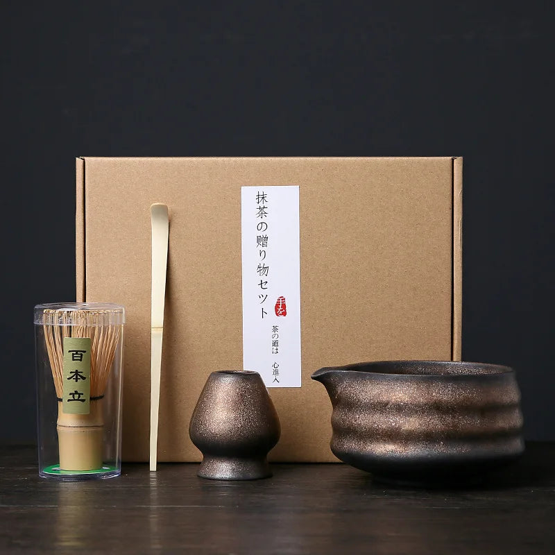 A set of Japanese matcha whisks and a ceramic bowl are displayed in a cardboard box.