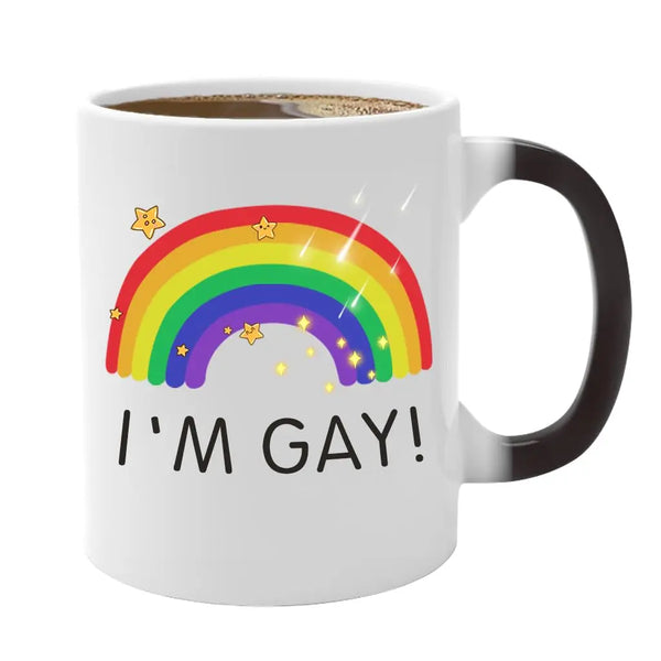 A white ceramic mug featuring a rainbow design and the text I'M GAY!