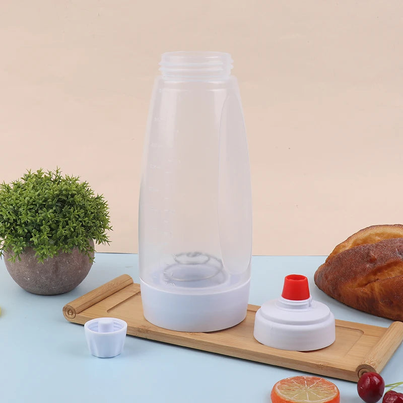 A clear plastic handheld batter mixer with a white base and red cap is shown on a wooden tray.
