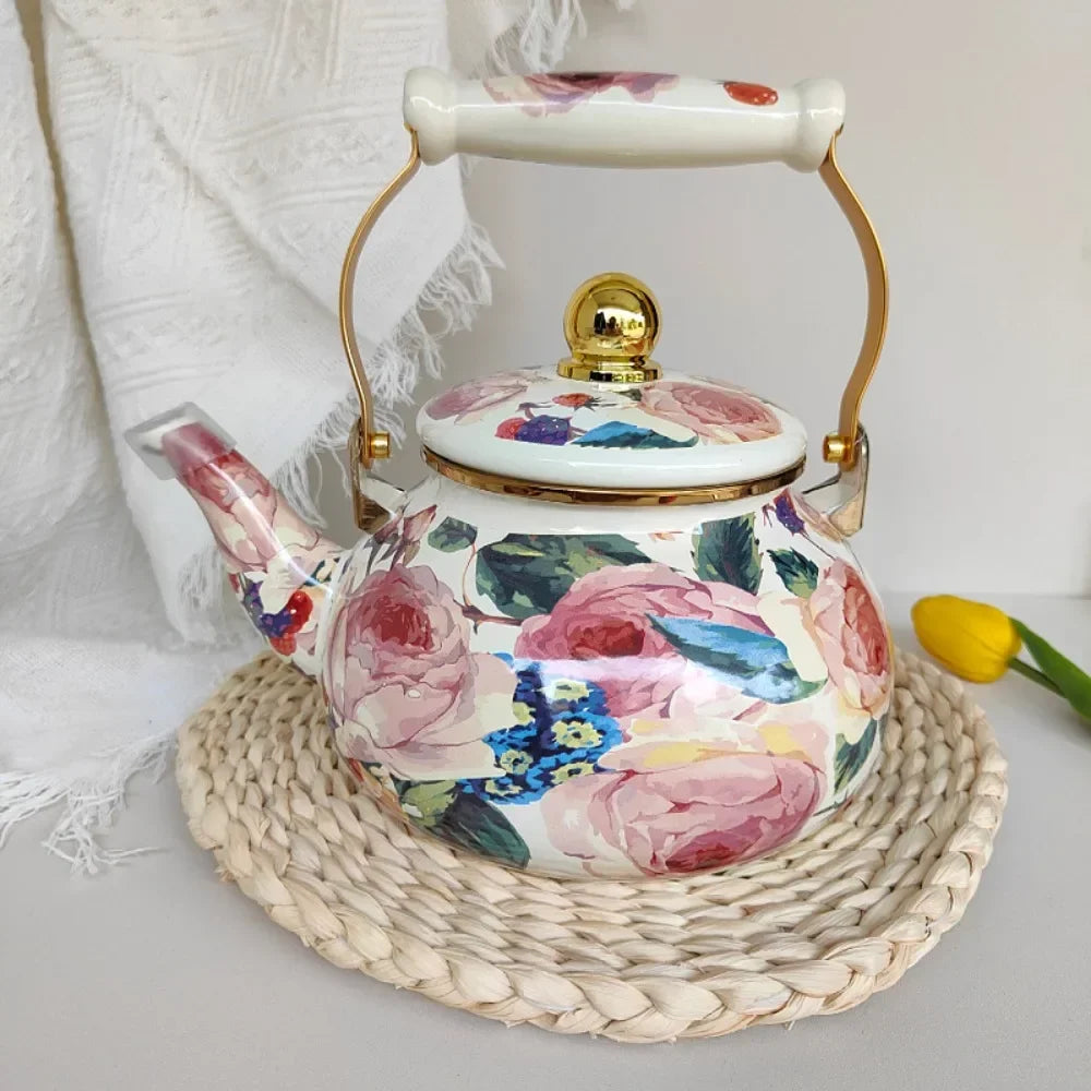 A white and pink floral enamel teapot with a gold handle sits on a woven mat.