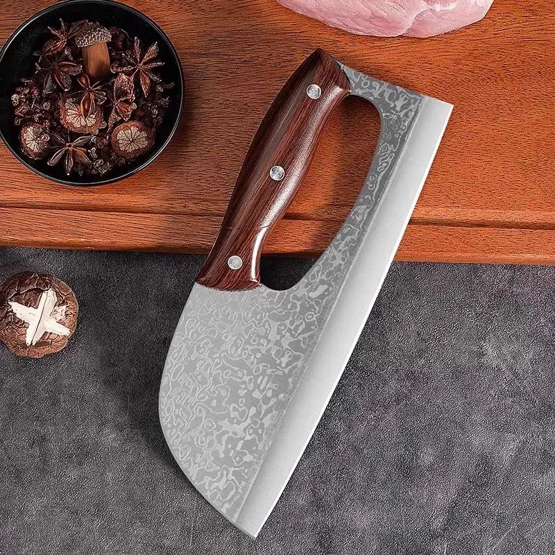 A hand-forged stainless steel chef knife with a wooden handle resting on a dark gray surface next to spices and a pink object
