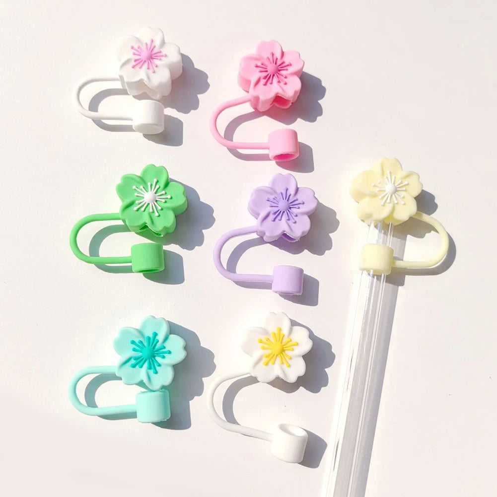 A collection of pink, purple, and green flower straw caps for tumblers arranged on a white background.