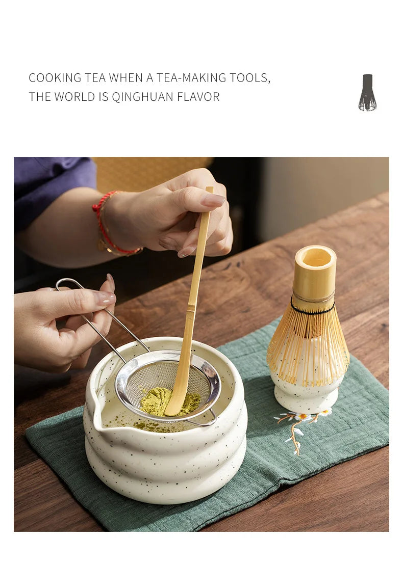 Hands prepare matcha tea using traditional tools and a bamboo whisk in a ceramic bowl.