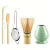 A set of natural bamboo tea tools including a spoon, strainer, and a green ceramic cup.