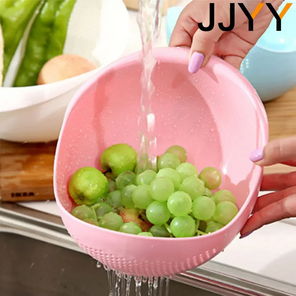A hand is pouring green grapes into a pink multi-use kitchen drainer colander.