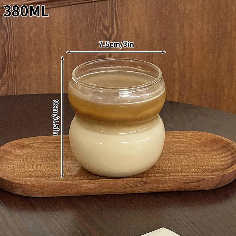 A clear glass tumbler filled with a light beige liquid sits on a wooden cutting board.