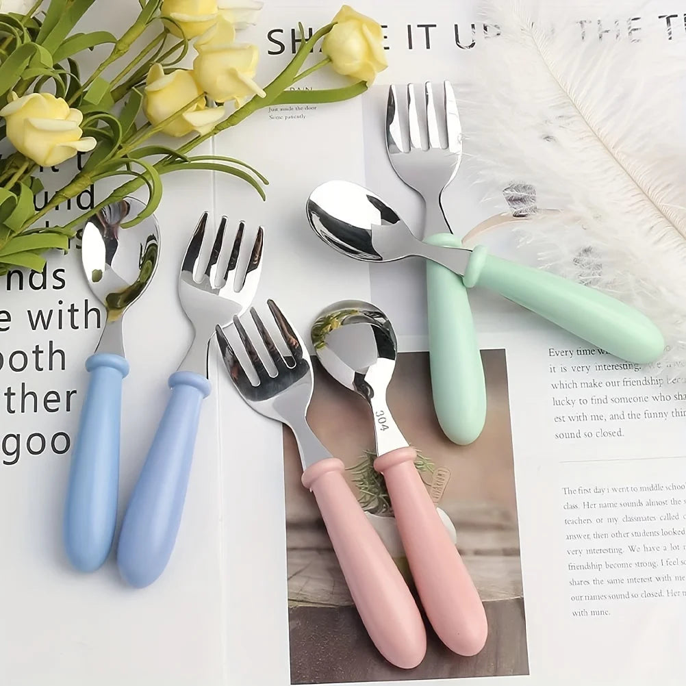Set aus Edelstahl-Kinderbesteck, einschließlich Gabel, Löffel und Messer in verschiedenen Pastellfarben.