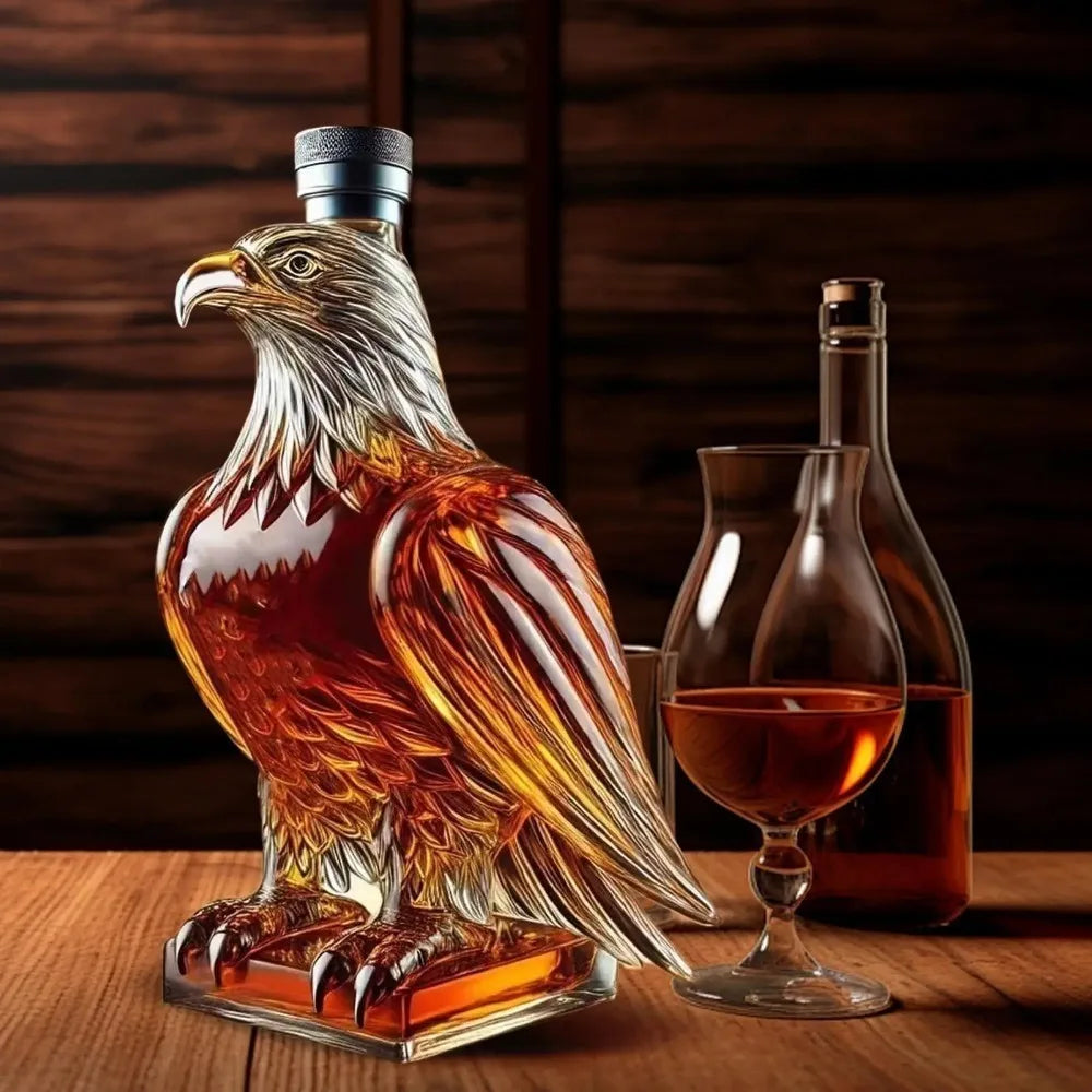 Un pichet en verre en forme d'aigle verse du whisky ambré dans un verre sur une surface en bois.