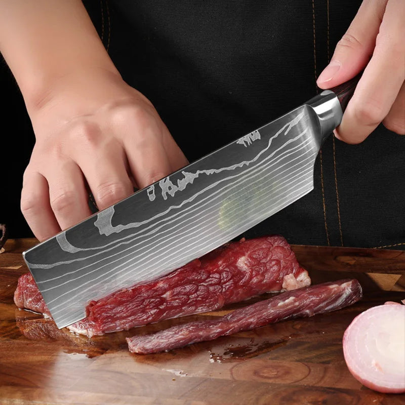 A hand holds a professional Damascus chef knife slicing through raw red meat on a wooden cutting board.