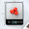 A black digital kitchen scale is shown measuring three red tomatoes on a white surface.