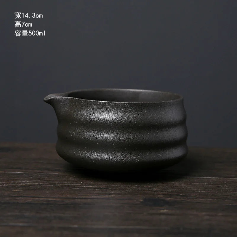 A dark gray ceramic matcha whisk or bowl resting on a wooden surface.