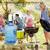 A blue portable electric water dispenser pump is placed on a wooden table outdoors near a grill.