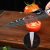 A professional Damascus chef knife is shown slicing a tomato on a wooden cutting board.