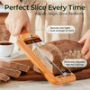 A hand uses an adjustable stainless steel bread slicer to slice a loaf of bread.