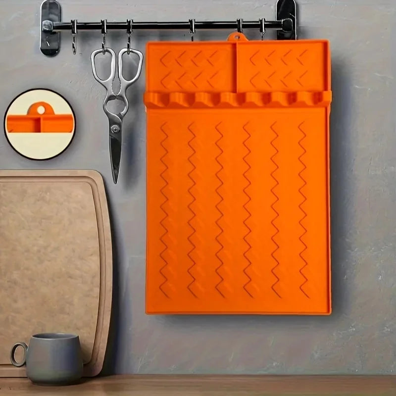 Orange silicone side burner rack and utensil storage mat hanging on a metal rack.