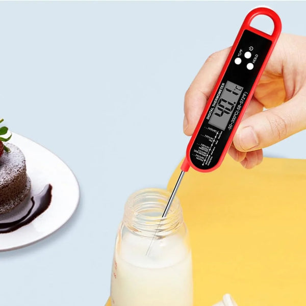 A hand holds a red digital meat thermometer measuring the internal temperature of milk in a glass bottle.
