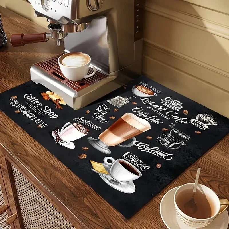 A black coffee drying mat is placed on a wooden table next to a silver coffee machine and a cup of coffee.