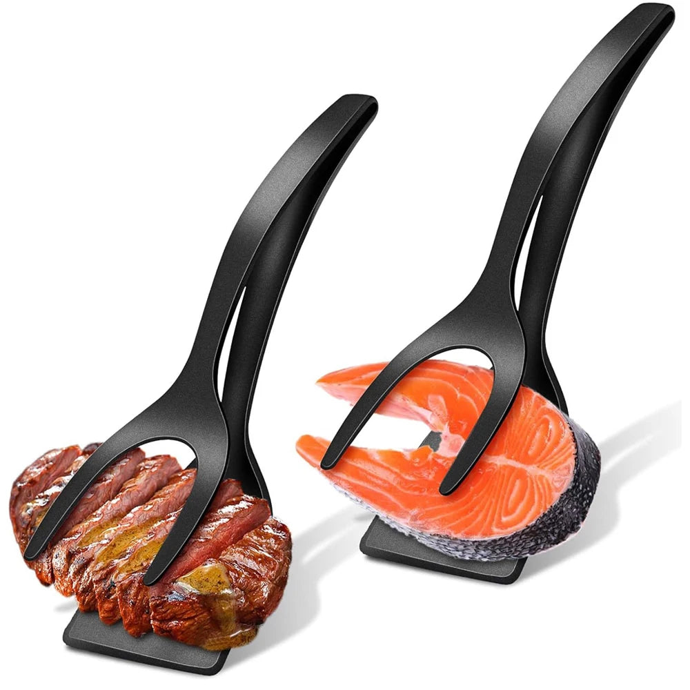 A pair of black silicone grip and flip spatulas are shown with a piece of cooked meat and salmon on a white background.