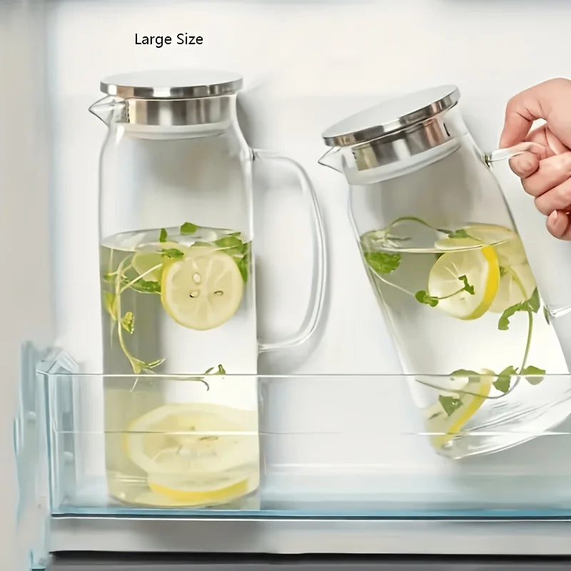 A glass water pitcher with a stainless steel lid is shown, filled with water and lemon slices.