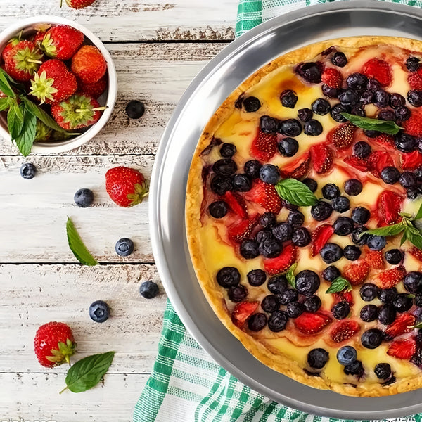 Runde Tarte oder Pizza in silberner Form, belegt mit frischen Erdbeeren, Blaubeeren und cremiger Füllung.