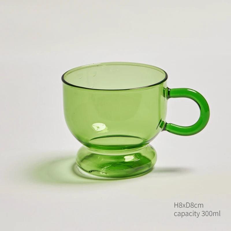 A clear green glass teacup and mug set with a pedestal base.