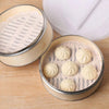 A set of reusable silicone steamer liners containing several round, white, pleated silicone cups.