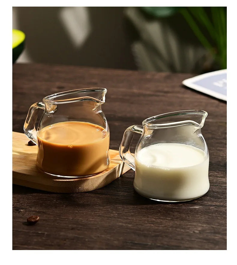 Two glass serving cups, one filled with brown liquid and the other with white milk, resting on a wooden board.