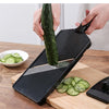 A hand is using a black vegetable grater tool to shred cucumber slices on a wooden cutting board.
