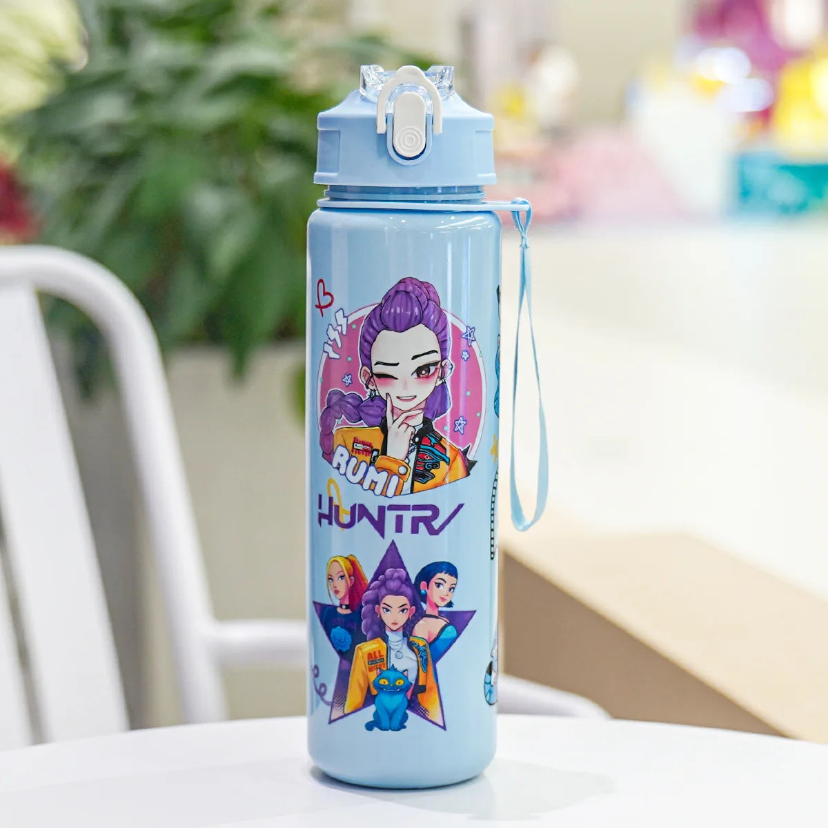 A light blue insulated water bottle with a cartoon print featuring female characters and the word HUNTR
