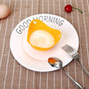 A white plate with a yellow silicone egg poacher mold, silverware, and a cherry on a beige checkered cloth.