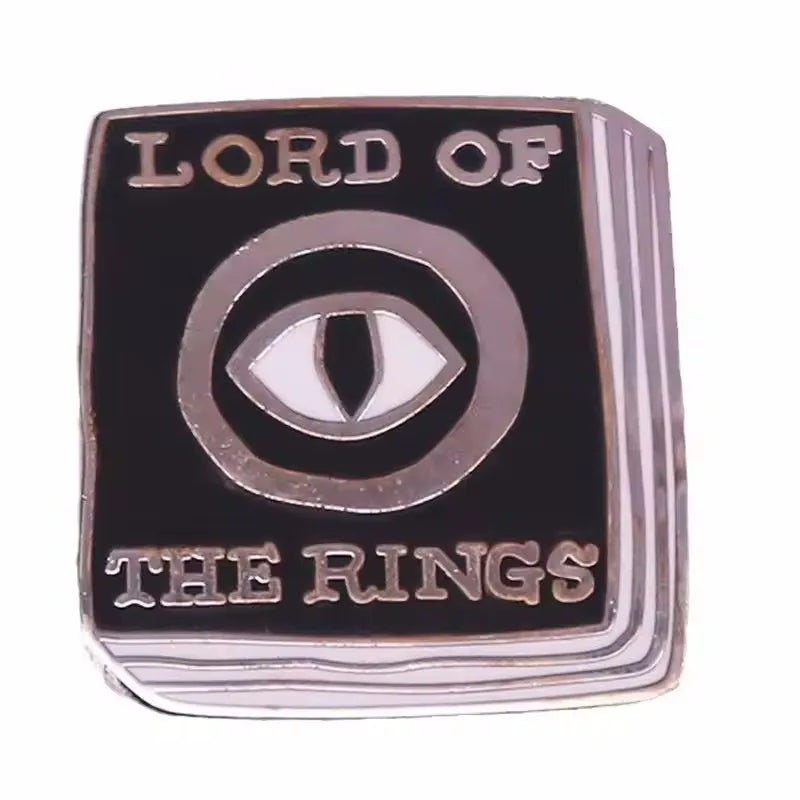 A black enamel pin featuring the text LORD OF THE RINGS and a stylized eye design.