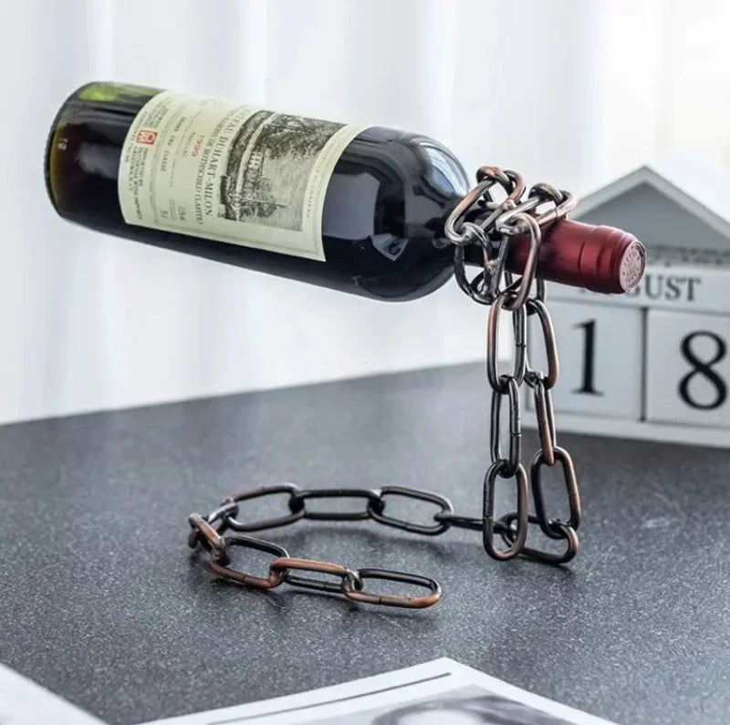 A dark wine bottle with a metal chain attached is displayed on a gray surface.