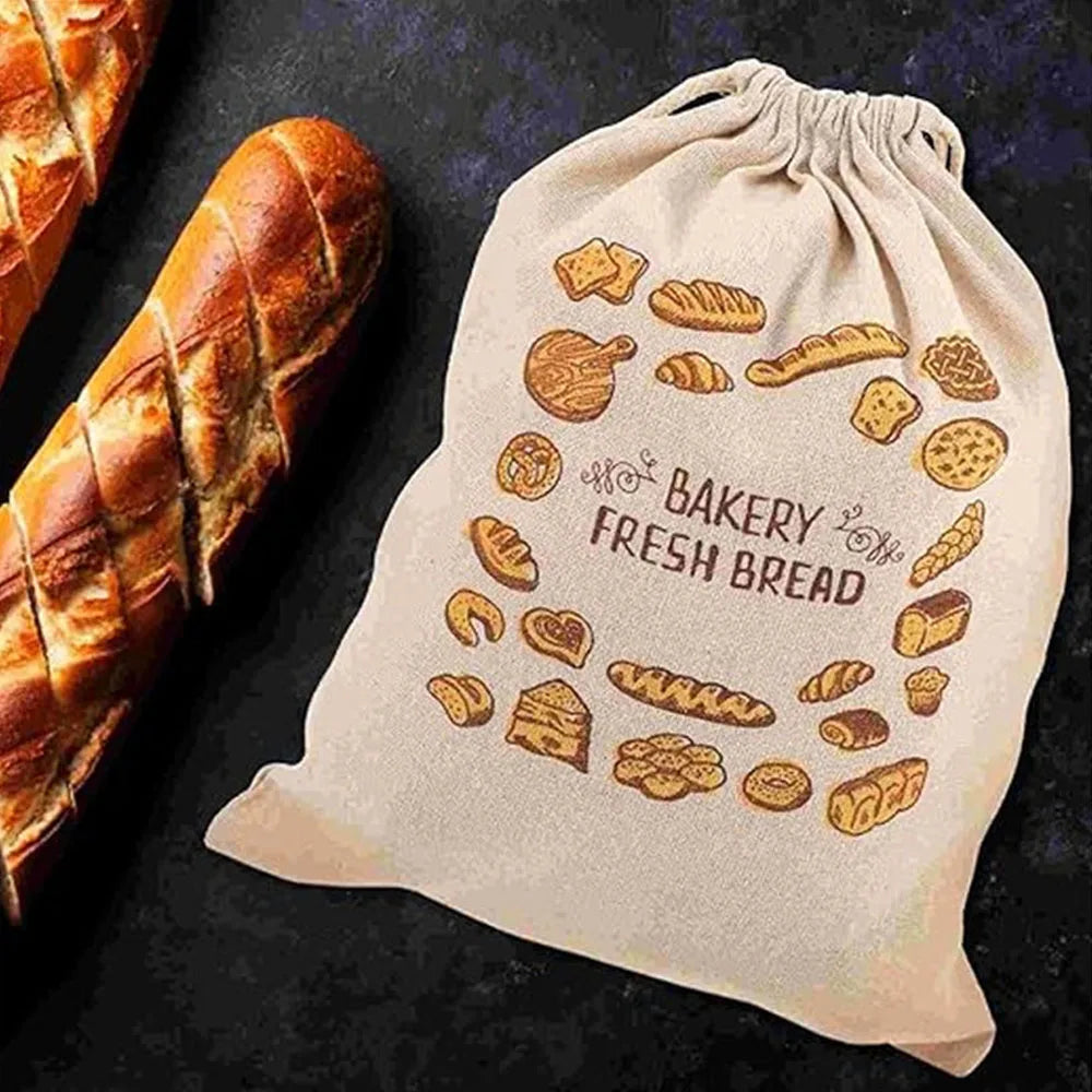A beige linen bread bag with a drawstring, featuring illustrations of various baked goods like croissants and rolls.