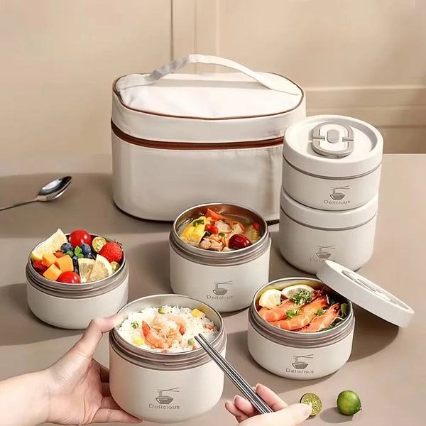 Eine Hand hält eine weiße, isolierte Edelstahl-Lunchbox mit Deckel und mehreren kleineren Behältern.