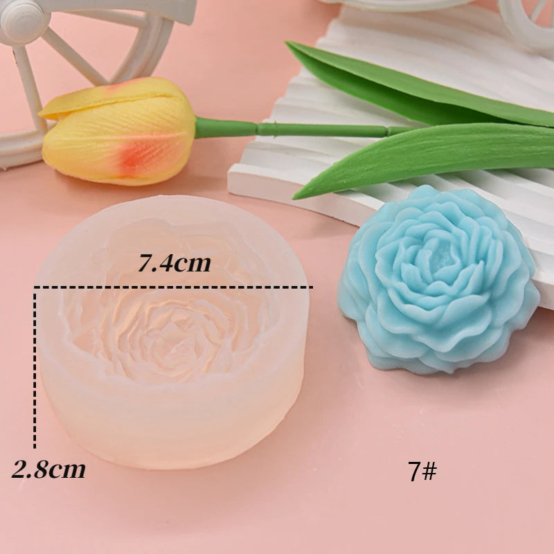A silicone flower candle mold in a pale pink color is shown next to a yellow tulip and green leaves.