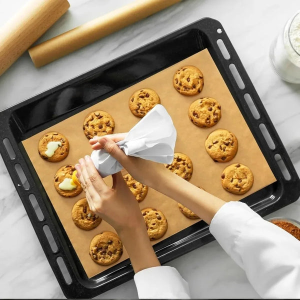 Hände legen Kekse auf ein Backblech mit Backpapier.
