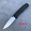 A black folding utility knife with a silver blade resting on a gray surface.
