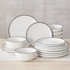 A stack of white porcelain dinnerware including plates and bowls with black rims on a wooden surface.