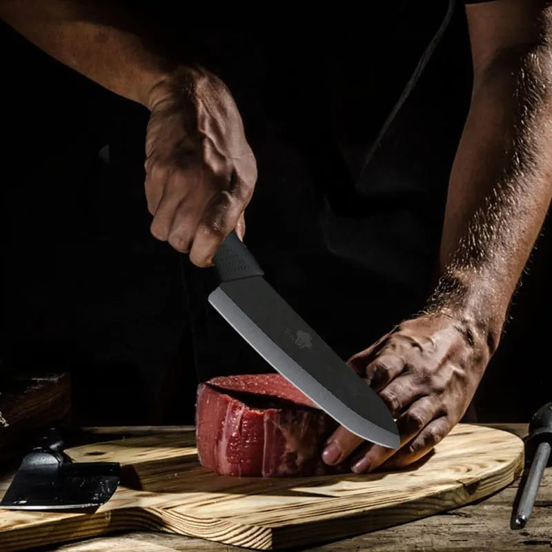 A person is using a ceramic chef knife to cut a raw red meat steak on a wooden cutting board.